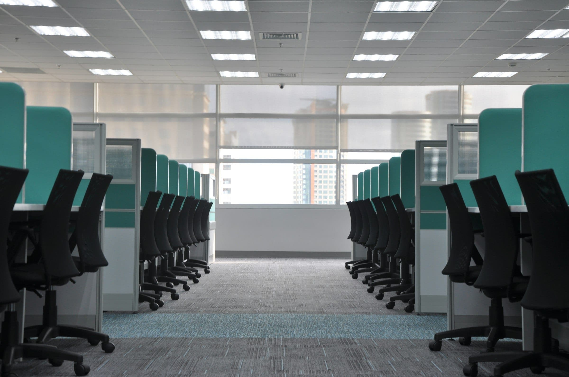 Rows of empty black office chairs at cubicles in an open plan office